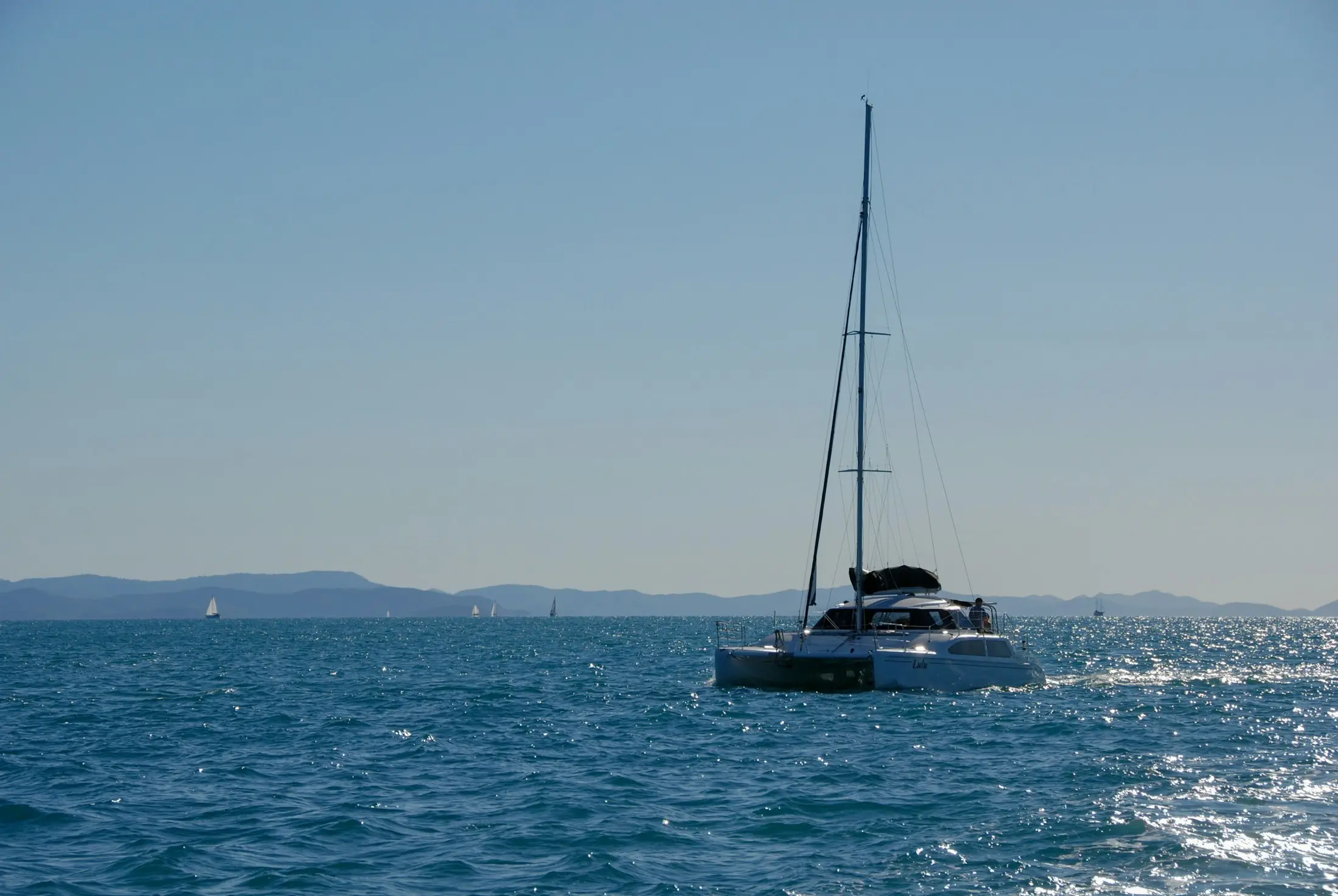 Sailing catamaran anchored on calm blue water