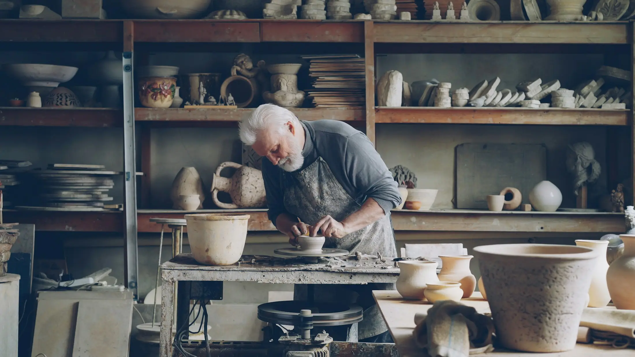 Potter shaping clay in a busy ceramics studio