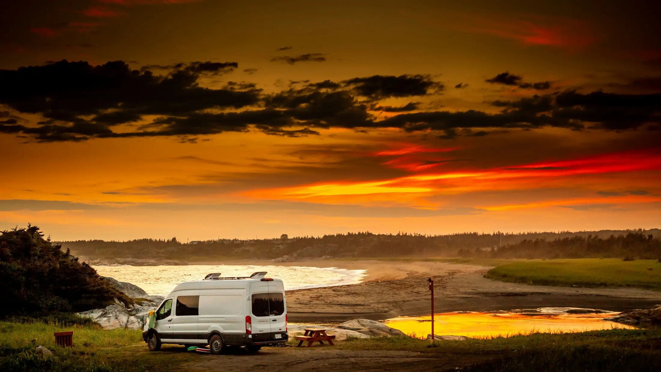 Caravan parked by a lake under a glowing sunset