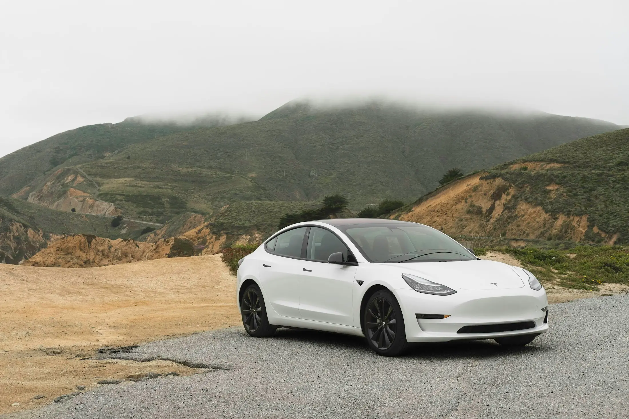 White electric car on a winding coastal road