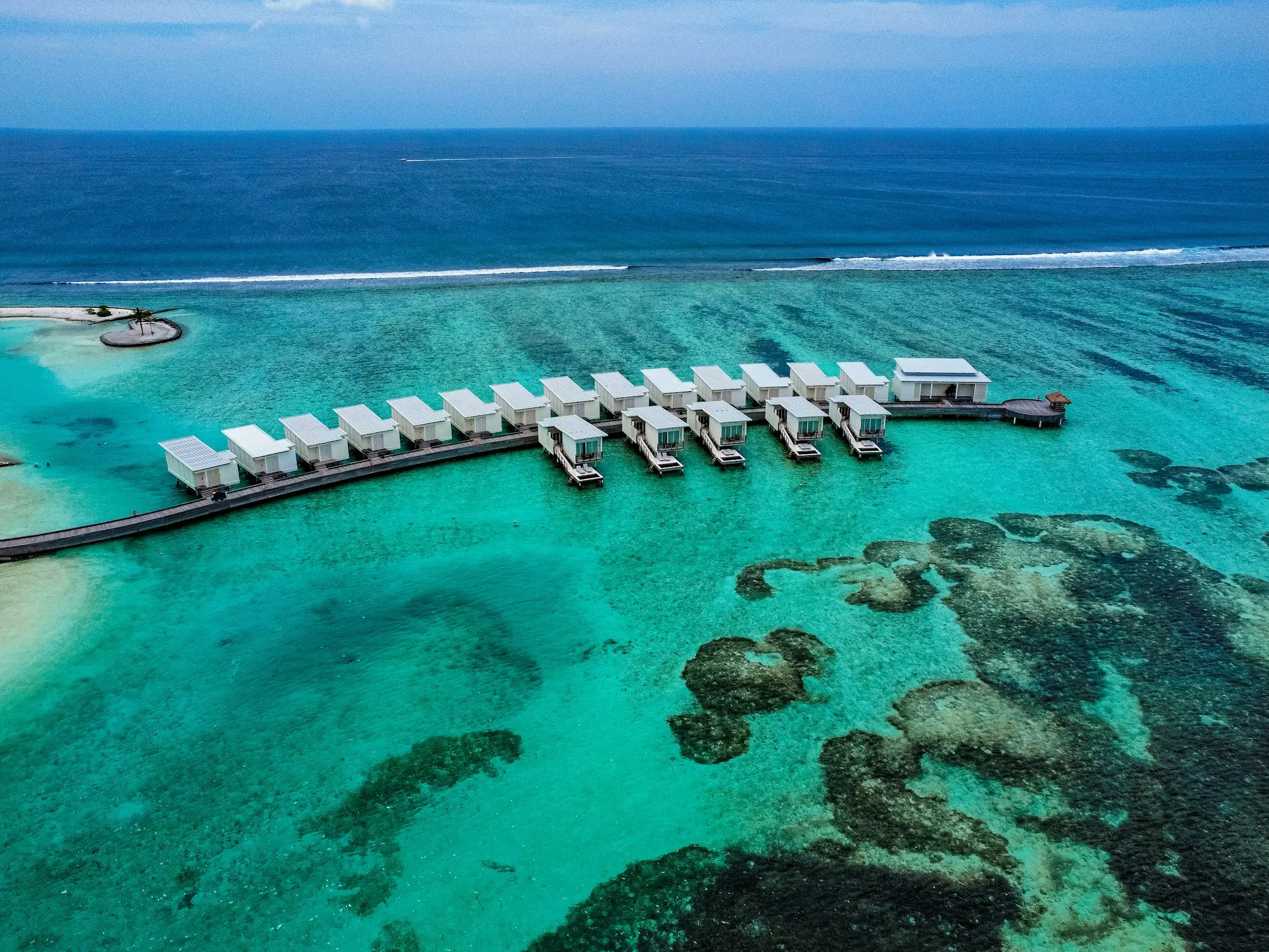 Aerial view of overwater bungalows above a turquoise reef
