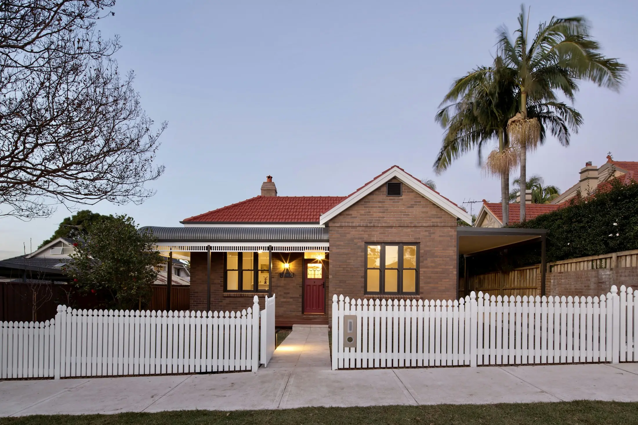 Brick home with a palm tree and white picket fence