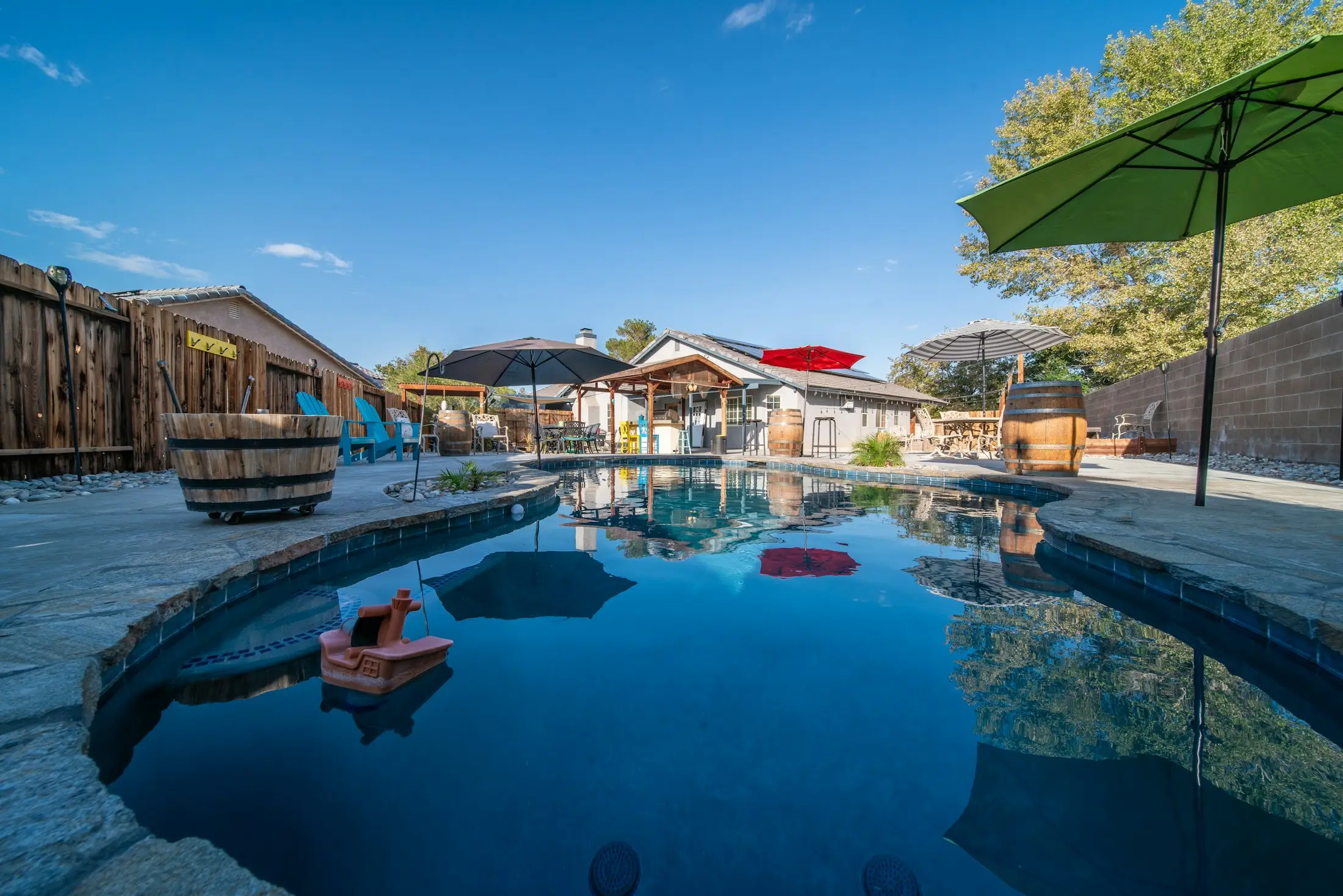 Backyard pool reflecting a blue sky beside an outdoor entertaining area