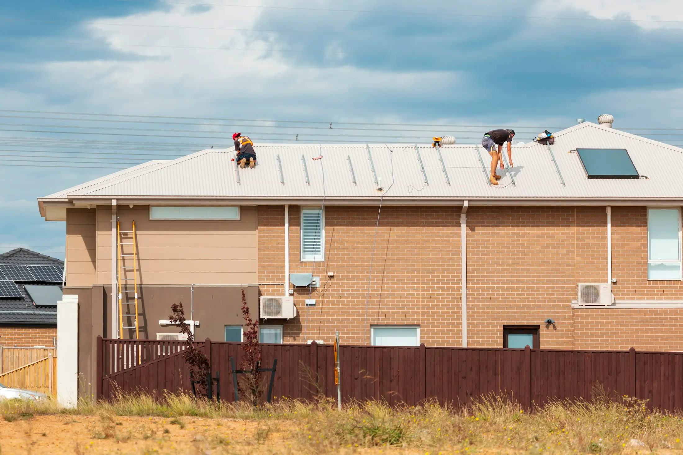 Installers on the roof of a brick Australian home