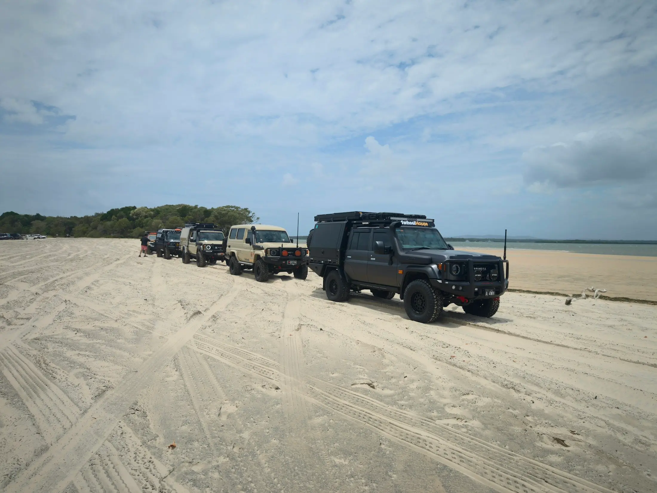 Convoy of four-wheel drives on a wide sandy beach