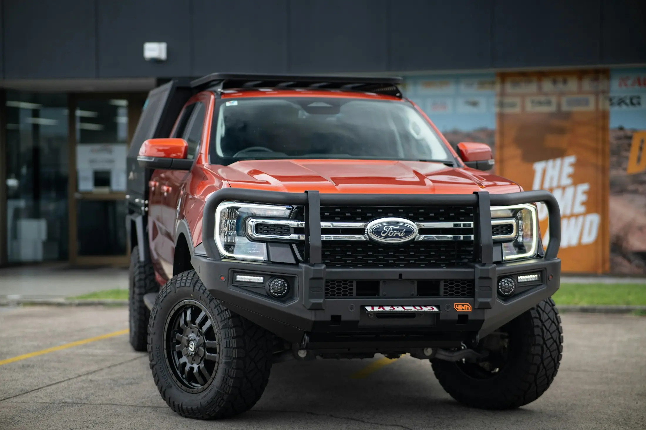 Orange dual-cab ute fitted with a steel bull bar and roof rack