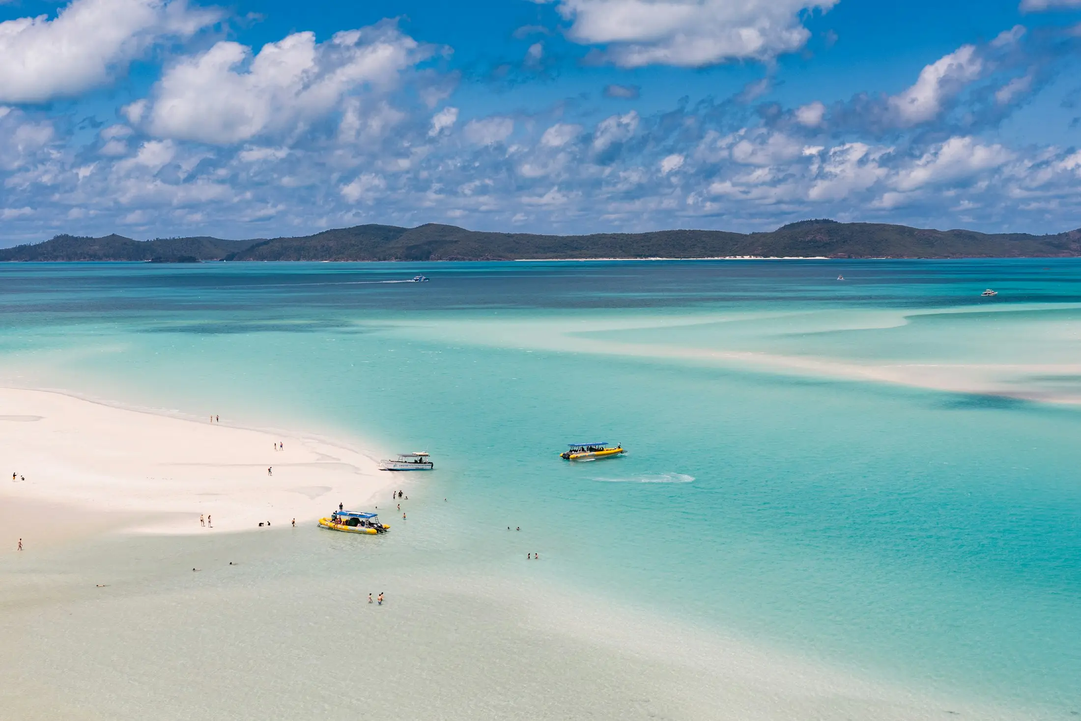 Small boats in the turquoise shallows beside the white sand of Whitehaven Beach in the Whitsundays